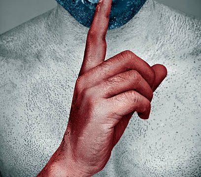 Painted man with naked body putting index finger on lips